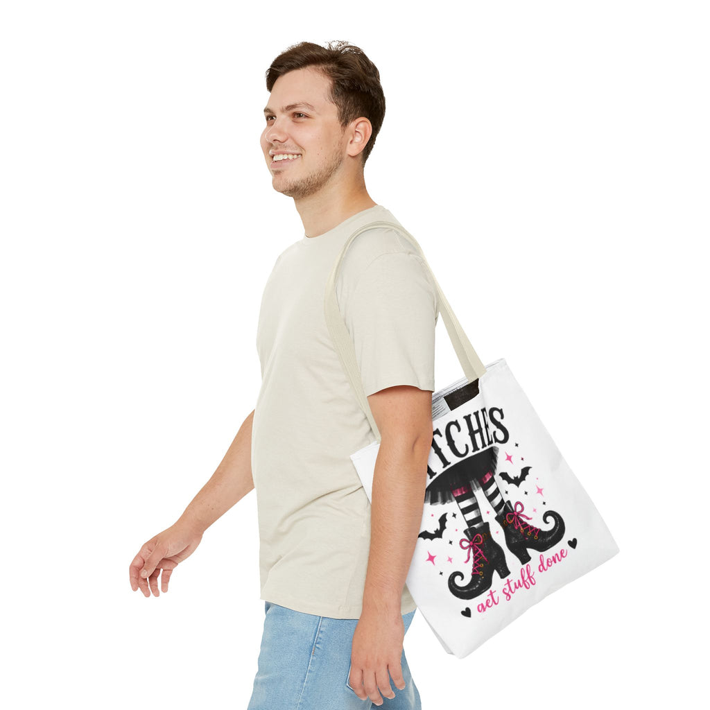 Cream canvas tote bag on shoulder with witch legs graphic and 'WITCHES' banner