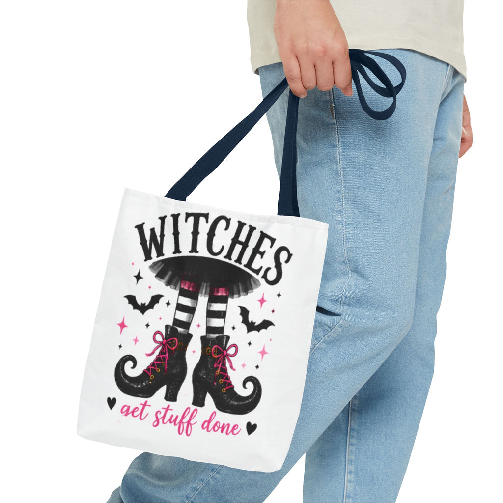 White tote bag with navy handles in hand, featuring witch boots and bats graphic