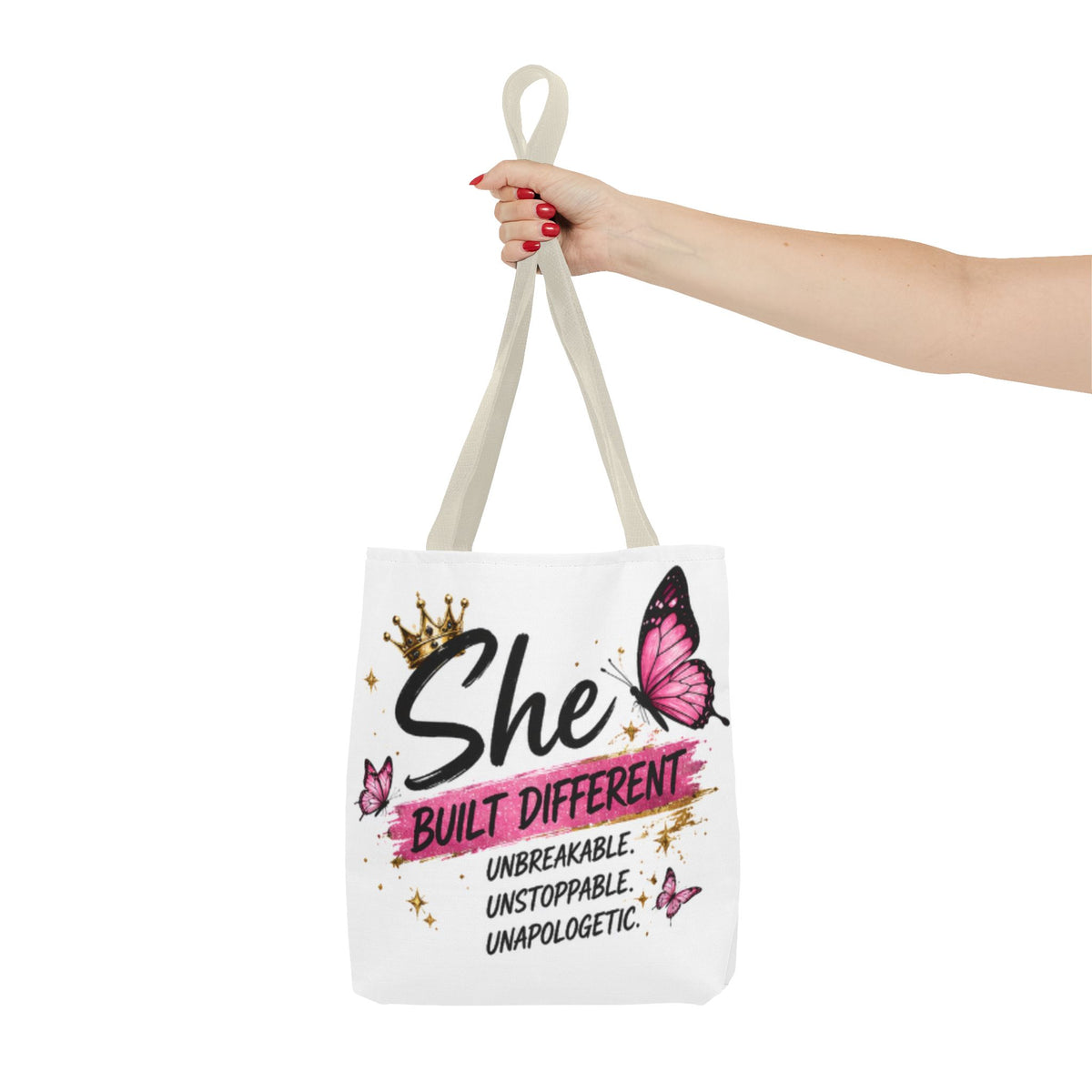 White canvas tote bag held by top handle, butterfly and “She Built Different” front print