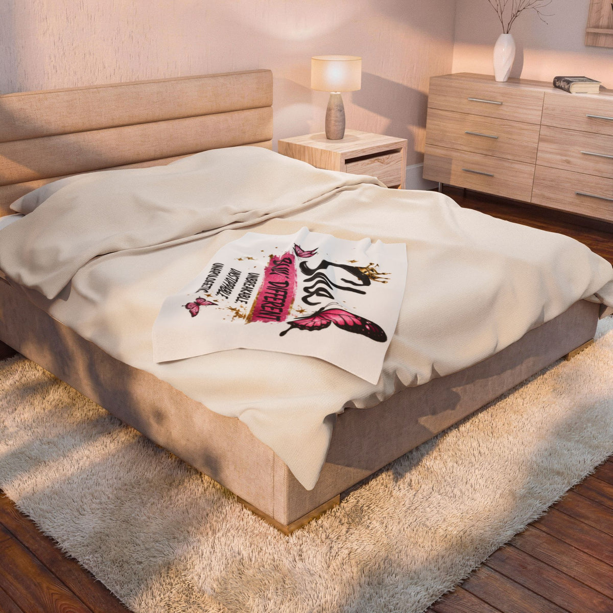 White velveteen plush blanket with pink butterfly 'Built Different' design, draped on bed
