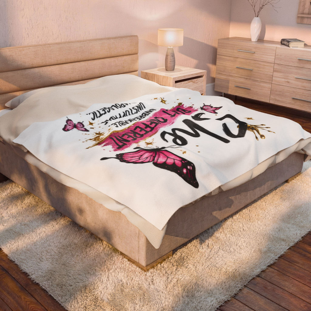 White plush blanket on bed with "Built Different" lettering and pink butterfly artwork