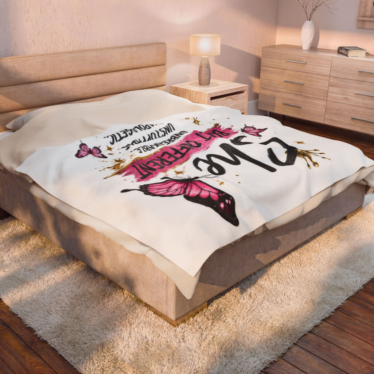 White plush blanket on bed with "Built Different" lettering and pink butterfly artwork