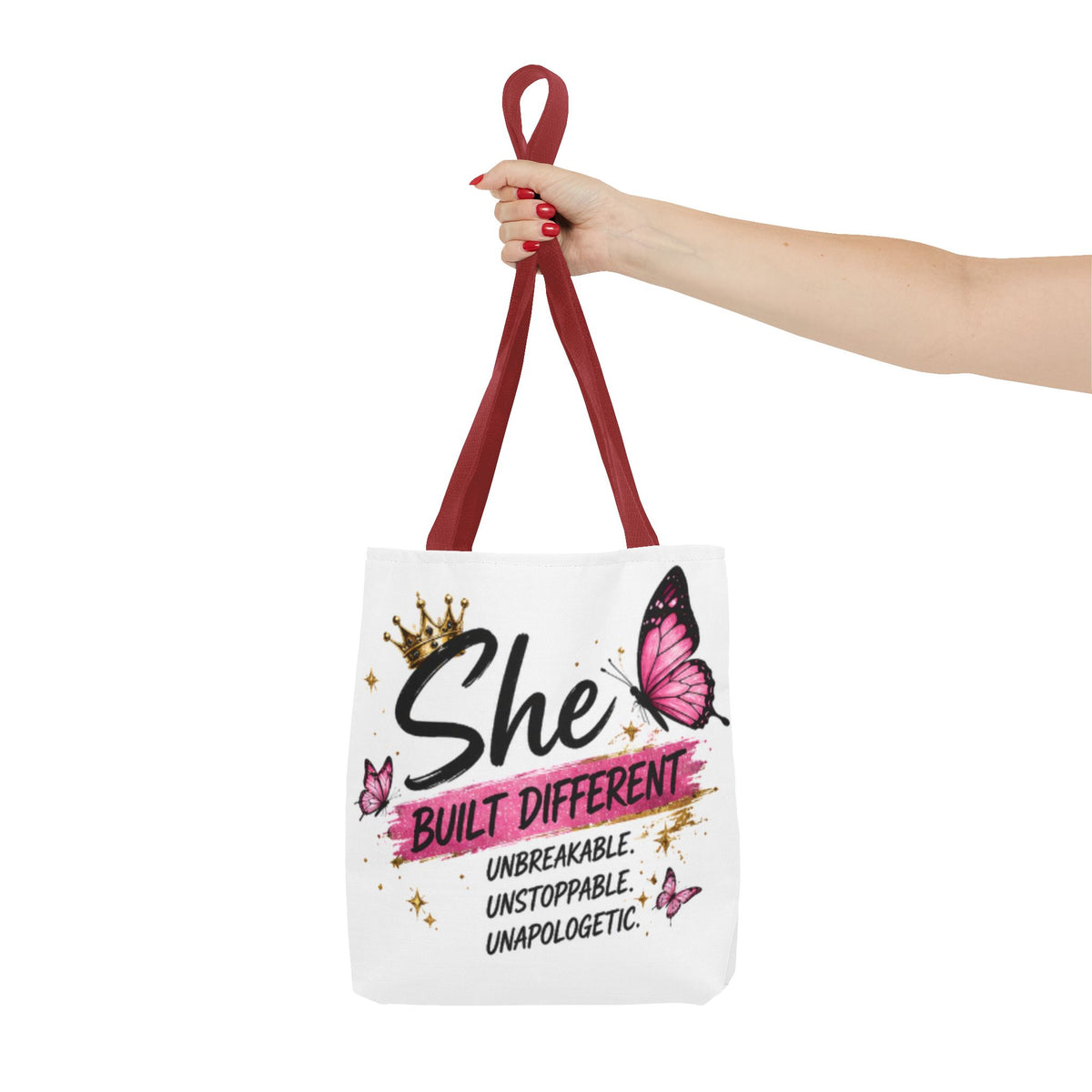 White tote bag held by burgundy handles, “She Built Different” and pink butterfly print