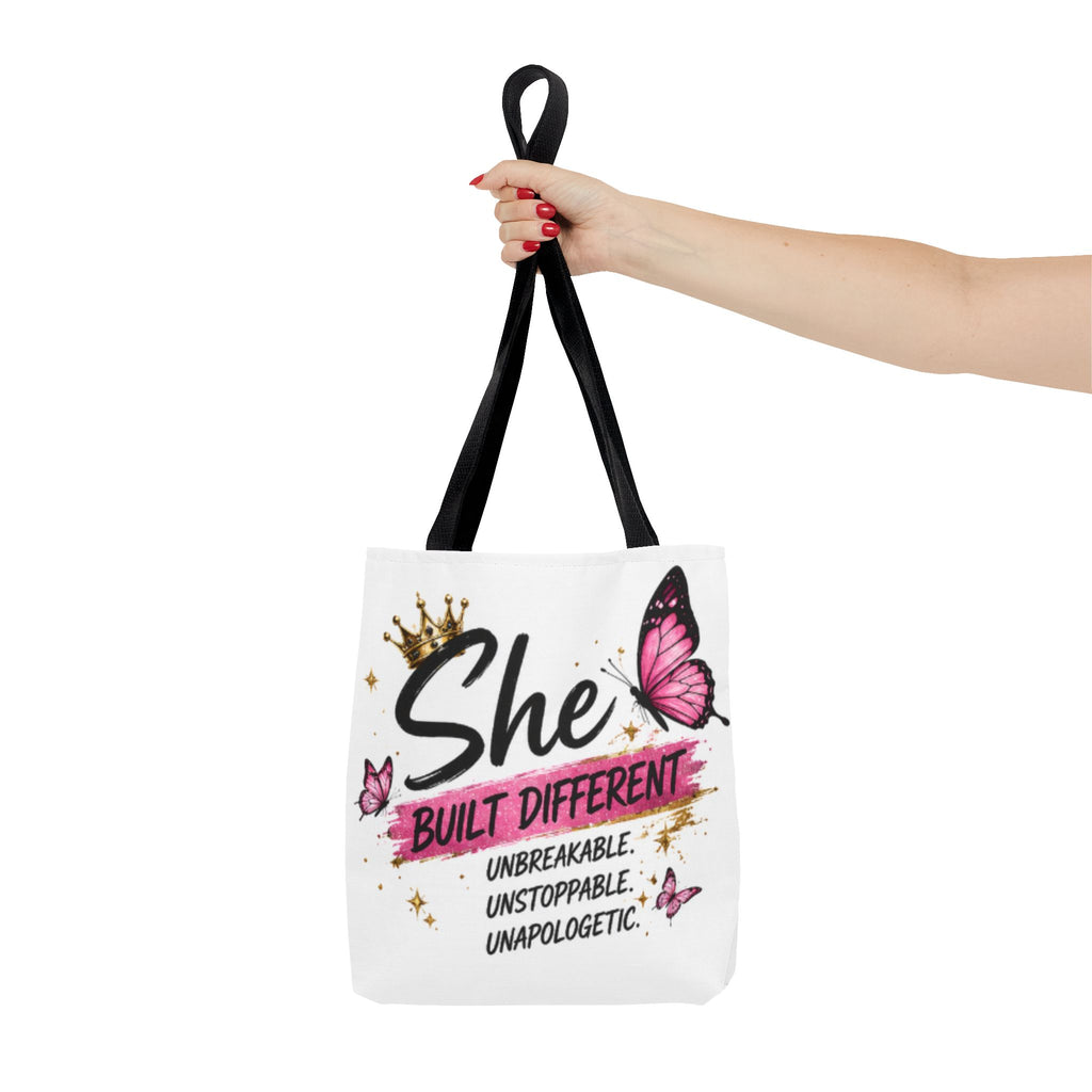 White tote bag with black handles, “She Built Different” crown and pink butterfly design
